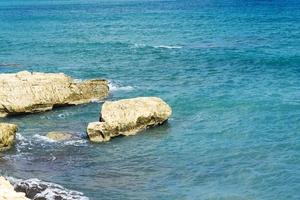 The waves breaking on a stony beach, forming a spray. Wave and splashes on beach. Waves crashing onto rocks. photo