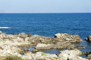 The waves breaking on a stony beach, forming a spray. Wave and splashes on beach. Waves crashing onto rocks. photo