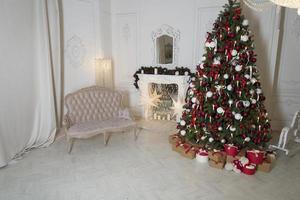 salón navideño con chimenea, sofá, árbol de navidad y regalos. hermoso interior de casa clásico decorado de año nuevo. foto