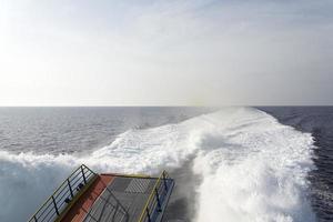 Trail on water surface behind of fast moving motor boat photo