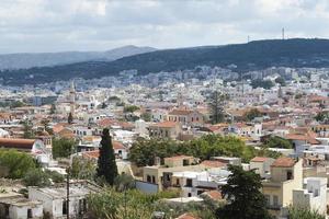 vista del complejo arquitectura griega ciudad-puerto de rethymno, construida por venecianos, desde la altura del castillo de fortezza - fortaleza en la colina paleokastro. techos de tejas rojas y montañas en el fondo. Creta. foto