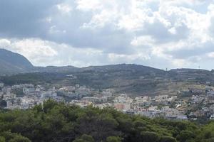 vista del complejo arquitectura griega ciudad-puerto de rethymno, construida por venecianos, desde la altura del castillo de fortezza - fortaleza en la colina paleokastro. techos de tejas rojas y montañas en el fondo. Creta. foto