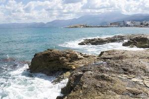 The waves breaking on a stony beach, forming a spray. Wave and splashes on beach. Waves crashing onto rocks. photo