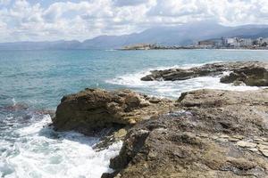 las olas rompiendo en una playa pedregosa, formando un rocío. olas y salpicaduras en la playa. olas rompiendo contra las rocas. foto