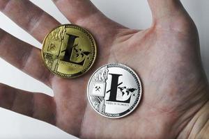 Hand holds two Litecoin on a white background. photo