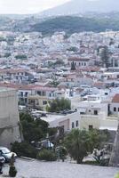 vista del complejo arquitectura griega ciudad-puerto de rethymno, construida por venecianos, desde la altura del castillo de fortezza - fortaleza en la colina paleokastro. techos de tejas rojas y montañas en el fondo. Creta.