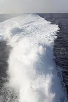 Trail on water surface behind of fast moving motor boat photo