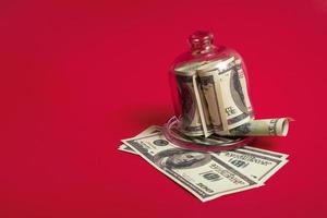 Leasing concept. Shopping cart and piggy bank with dollar bills on red background, closeup. Copy space photo