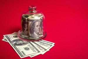 Leasing concept. Shopping cart and piggy bank with dollar bills on red background, close up photo