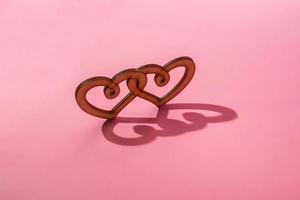 Wooden heart with hard shadow on a pink background. Trendy background for valentine's day. photo