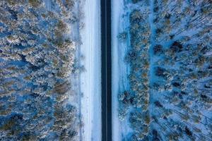 Aerial view on the road and forest at the winter time. Natural winter landscape from air. Forest under snow a the winter time. Landscape from drone photo