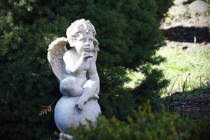 Cute cupid angel statue sitting in park photo