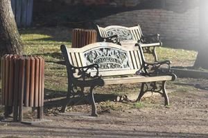 Wooden carved bench in park with trash bin photo