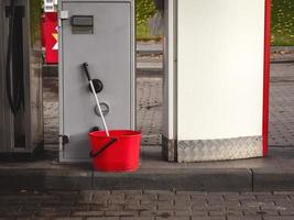 Red plastic bucket with mop at gas station photo