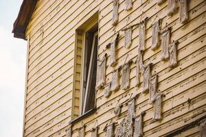 Yellow plank building wall with window and macrame weaved decorations photo