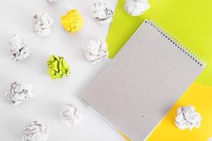 organic paper notebook among crumpled paper and colored paper on white background. zero waste concept photo