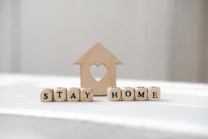 stay home letters on a dice near wooden toy house. photo