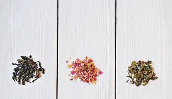 Different types of tea leaves on wooden background. photo