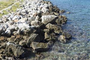 The waves breaking on a stony beach, forming a spray. Wave and splashes on beach. Waves crashing onto rocks. photo