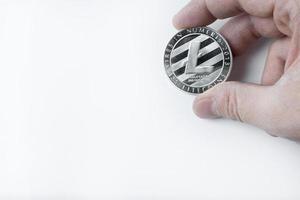 Hand holds one Litecoin on a white background. photo