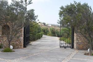 Park entry with open wrought-iron gate in gradient back and shut off the track