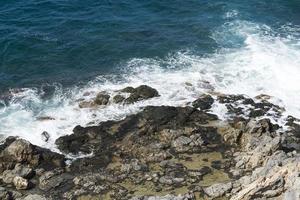 las olas rompiendo en una playa pedregosa, formando un rocío. olas y salpicaduras en la playa. olas rompiendo contra las rocas.