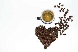 A cup of espresso with froth next to coffee beans laid out in the shape of a heart. Lifestyle. Your own space. Flatlay. Copispace. photo