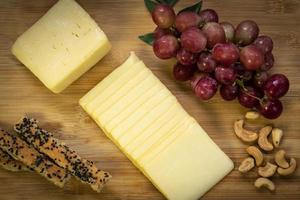 Sliced cheddar cheese block on wood board photo