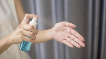 woman is cleaning her hands with alcohol spray photo