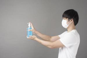 A handsome man with surgical mask is using alcohol hand sanitizer photo