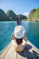 View of woman in swimsuit enjoying on thai traditional longtail Boat over beautiful mountain and ocean, Phi phi Islands, Thailand
