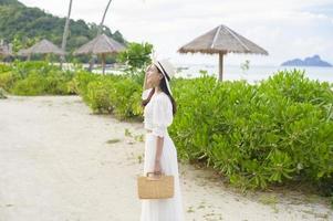 A happy beautiful woman in white dress enjoying and relaxing on the beach, Summer and holidays concept photo
