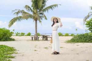 A happy beautiful woman in white dress enjoying and relaxing on the beach, Summer and holidays concept photo