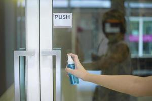 mujer está limpiando la manija de la puerta con spray de alcohol foto