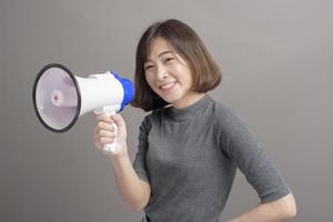 retrato de una joven y hermosa mujer asiática sosteniendo un megáfono sobre el fondo del estudio. foto