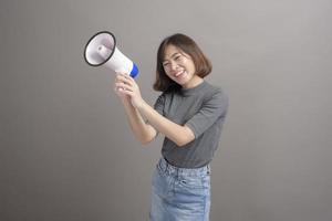 retrato de una joven y hermosa mujer asiática sosteniendo un megáfono sobre el fondo del estudio. foto
