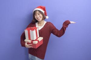 retrato de una mujer hermosa con sombrero rojo de santa claus sosteniendo una caja de regalo sobre fondo de estudio, concepto de navidad y año nuevo foto