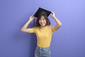 Portrait of young Asian student wearing graduation cap over studio background. photo