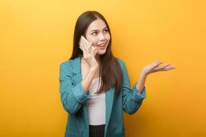 Fashion portrait of beautiful woman in green suit  using cellphone on yellow background photo