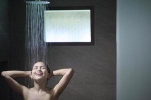 mujer hermosa joven duchándose en un baño en casa foto