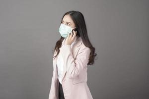 Business woman with surgical mask is using cell phone photo