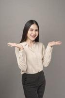 Portrait of Beautiful business woman is showing something on gray background photo