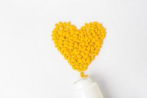 Heaps of yellow vitamins pills on white background photo