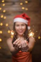 Portrait of beautiful woman wearing red Santa Claus holding sparklers at home, Christmas and New Year Concept. photo
