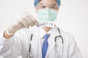 Doctor is holding Covid-19 card on white background photo