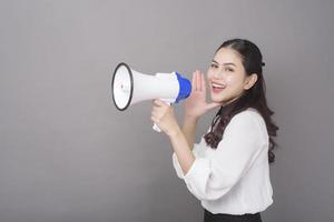 hermosa mujer asiática sosteniendo un megáfono en un estudio de fondo gris foto