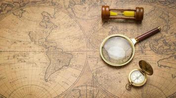 Old compass , magnifying glass and sand clock  on vintage map photo