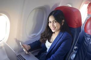 A young businesswoman wearing in blue suit is using laptop onboard photo