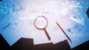 Magnifying glass and documents with analytics data lying on table photo