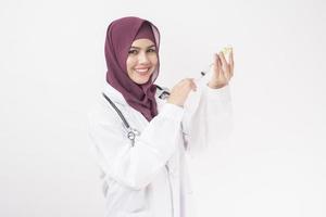 Beautiful woman doctor with hijab is holding vaccine  on white background photo